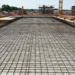 Wykonana płyta fundamentowa z widokiem zbrojenia stalowego i wyrównanej powierzchni betonu