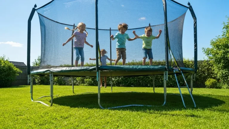 Dzieci skaczące na trampolinie ogrodowej z siatką ochronną w słonecznym ogrodzie